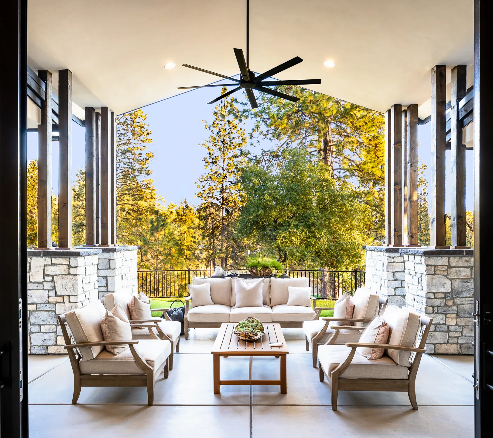 Covered outdoor living room with stone-wrapped timber columns overlooking the pines of Winchester Country Club