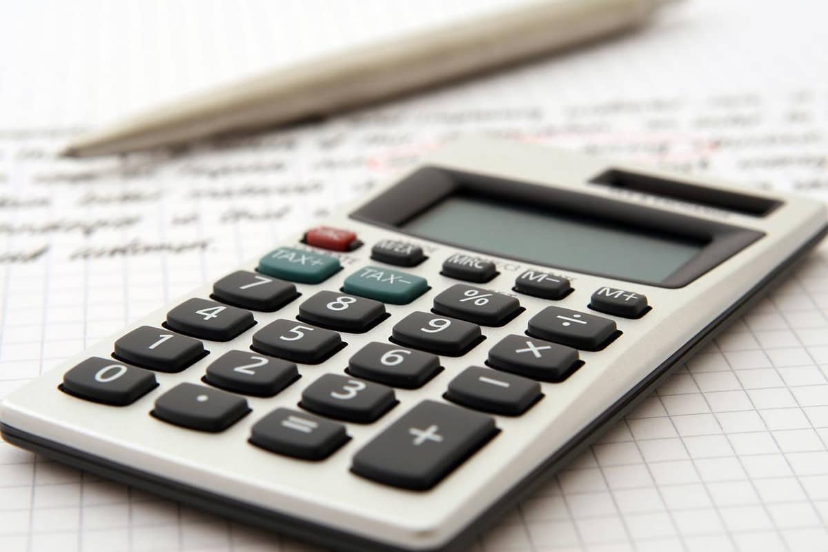 Calculator and pen resting on handwritten budget notes and graph paper