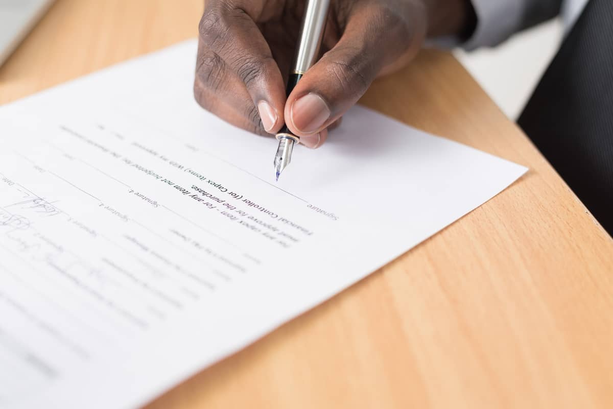 Close-up of a hand signing an approval form with a fountain pen