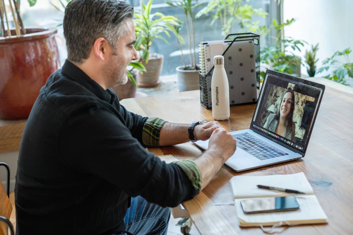 Man smiling during a video call on his laptop at a plant-filled desk