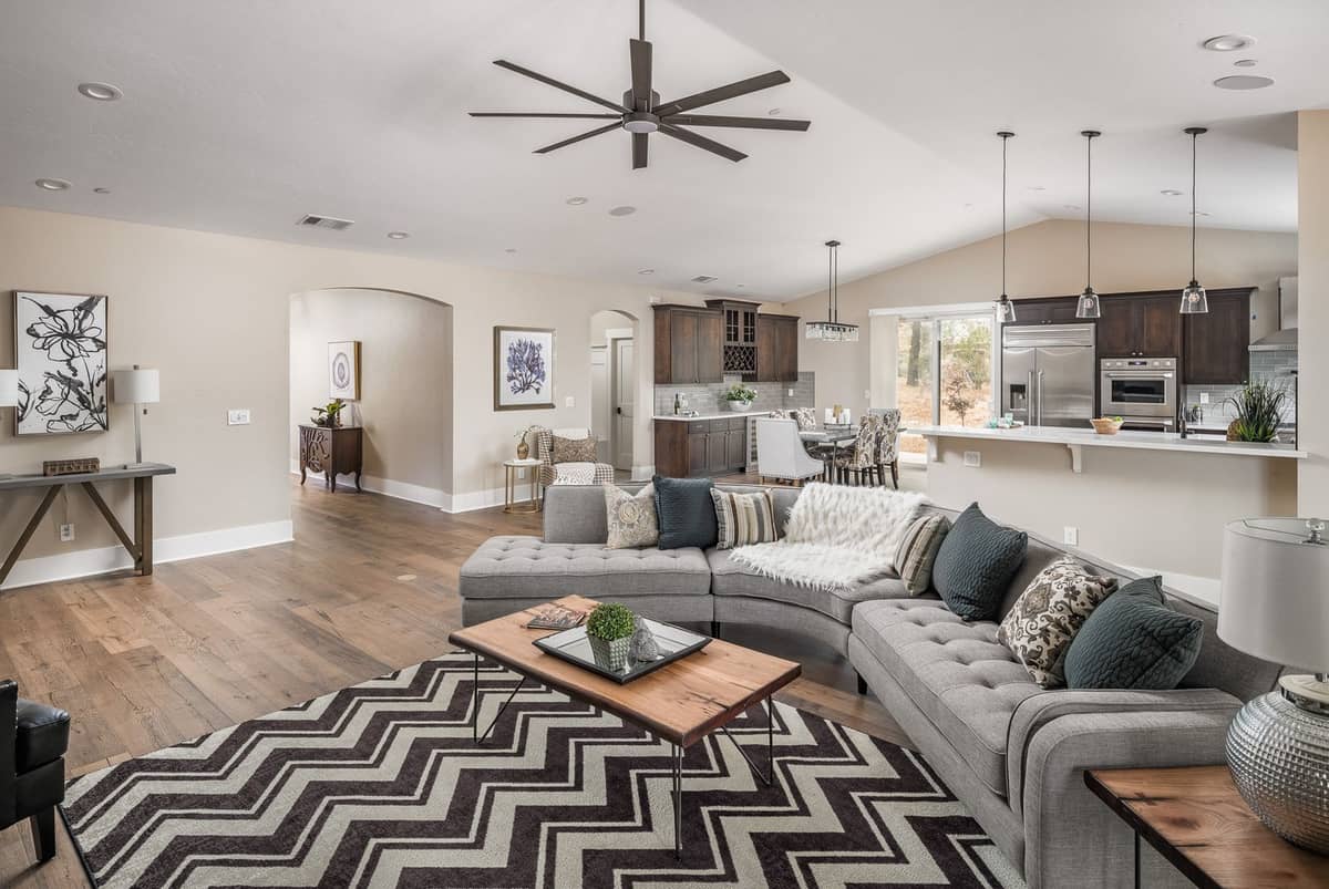Open-concept living room with gray sectional flowing into a dark-wood kitchen and dining area