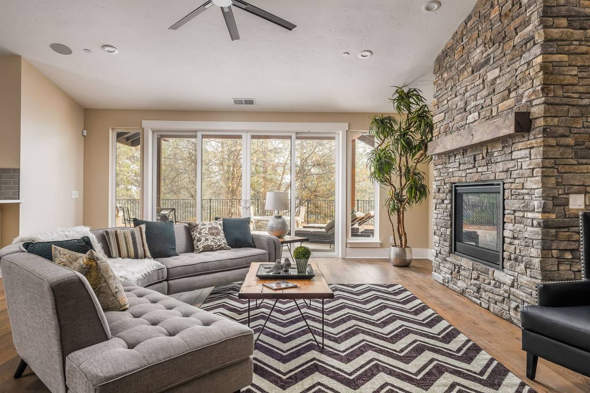 Living room with floor-to-ceiling stone fireplace and sliding glass doors opening to a covered deck