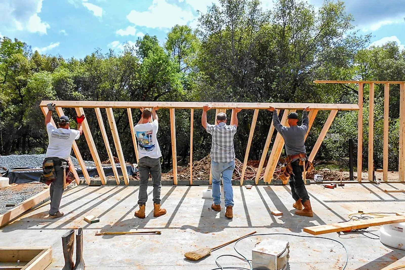 Four framers raising a stud wall on a concrete slab at a foothill custom home build site